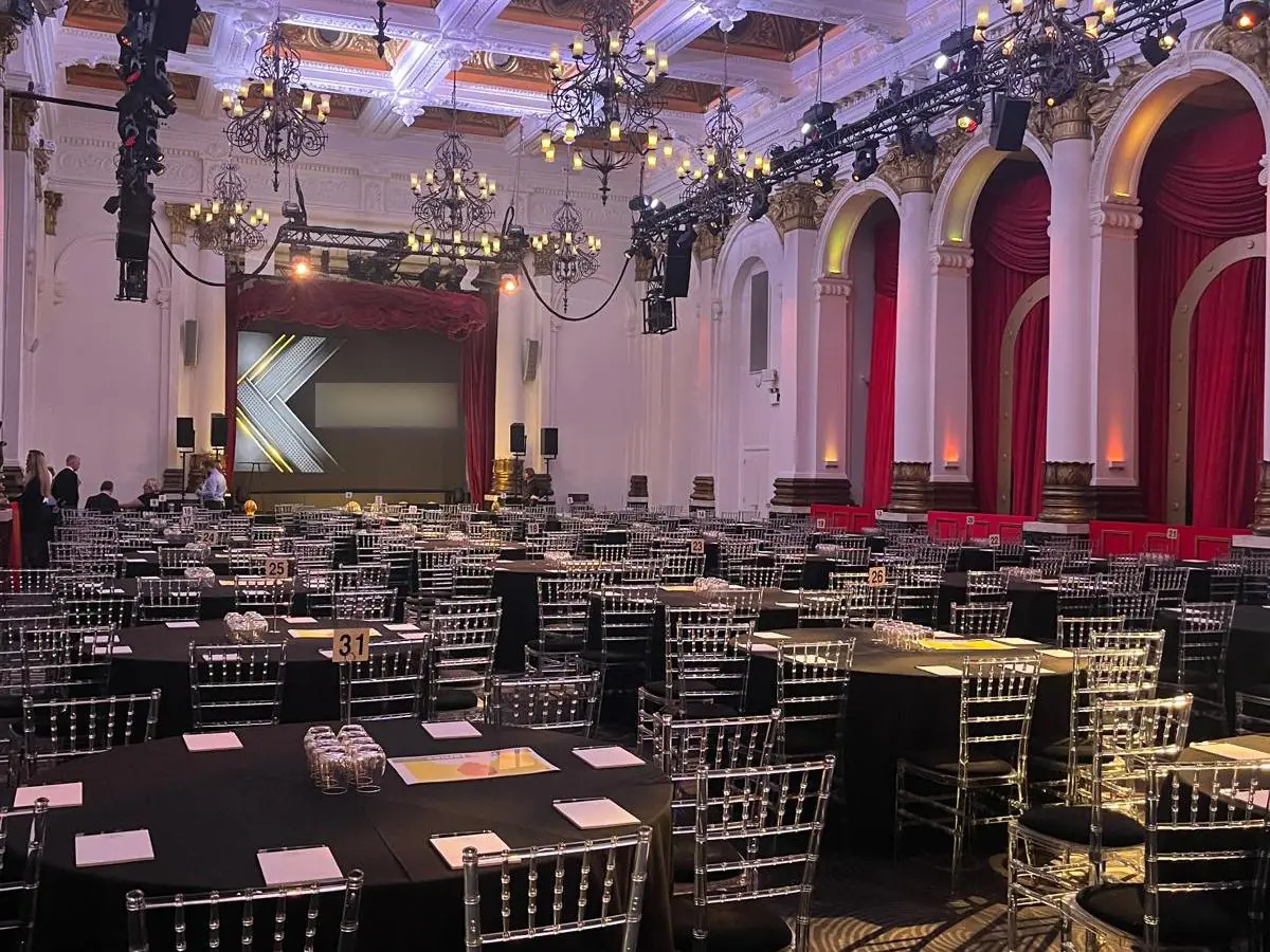 A historic banqueting hall set with round tables for a corporate dinner